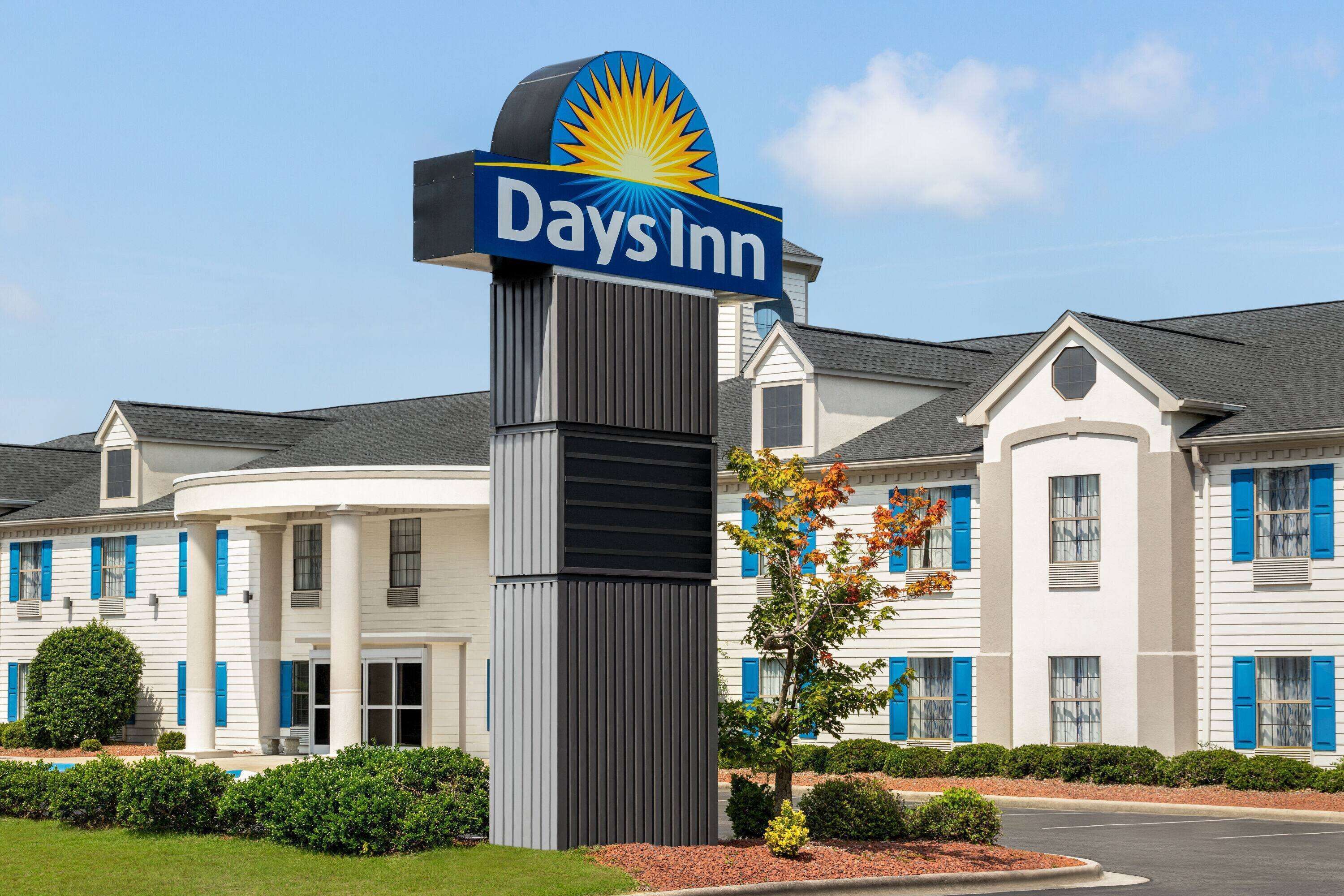 A Days Inn hotel with a prominent sign, a central entrance, and a symmetrical facade with blue shutters.