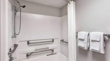 Een badkamer met een douche, handgrepen en een handdoekhouder.