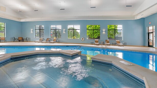 A swimming pool with lounge chairs and a view of trees through large windows. - Holiday Inn Express Breezewood by IHG (Breezewood)