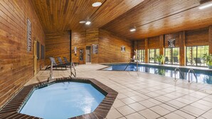 Una piscina interior con revestimiento de madera, suelo de baldosas y sillas de descanso.