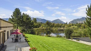 Un patio con mobiliario exterior, vistas a un lago y montañas al fondo.