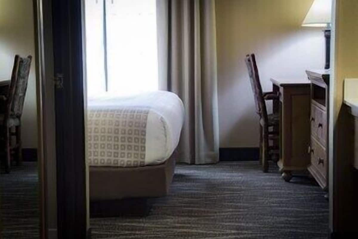 A hotel room with a bed, a dresser, and a chair.