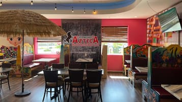A restaurant interior with wooden tables, chairs, and a large mural.