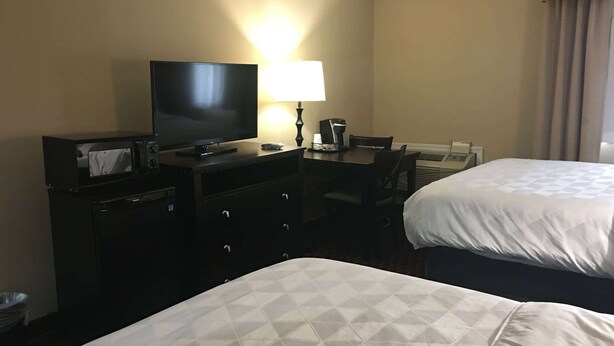 A hotel room with two beds, a television, a desk with a lamp, and a minibar. - Wyndham Garden Dover (Dover)