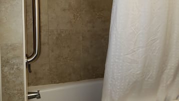 A bathroom with a shower, a handrail, a soap dish, and a towel rack.