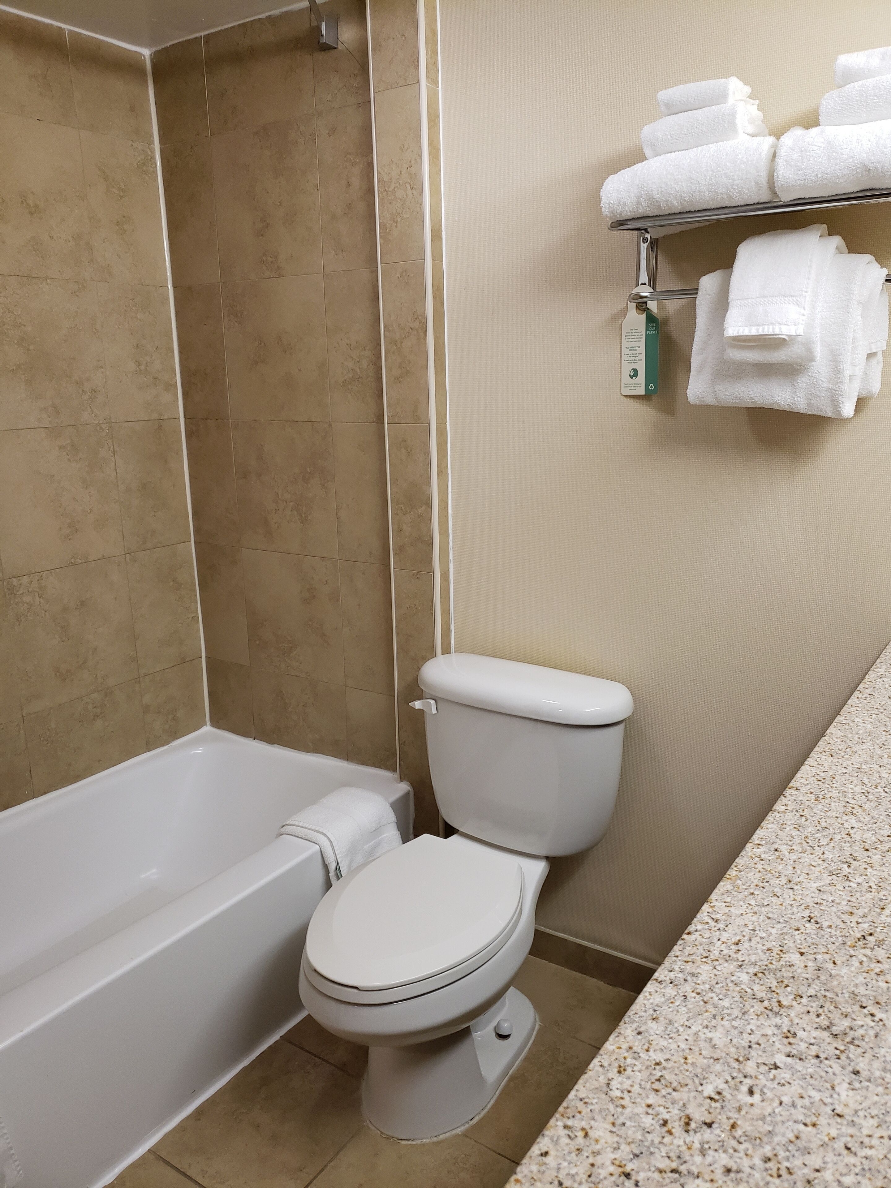 Un baño con una bañera blanca, inodoro y un perchero con toallas dobladas.