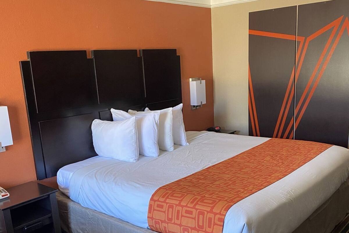 Ein Hotelzimmer mit einem großen Bett, einem Nachttisch, einem Sessel und einem Kleiderschrank.