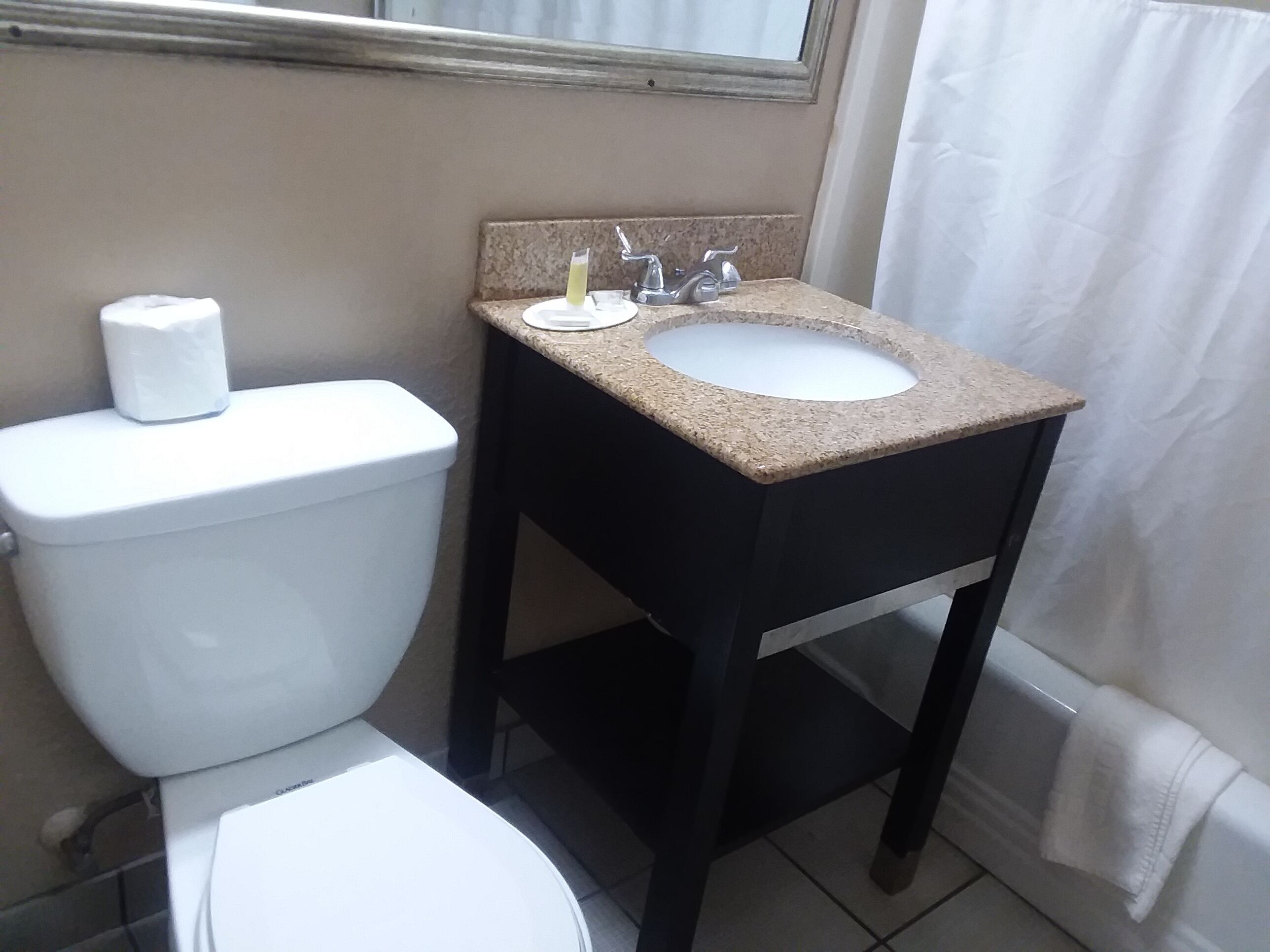 Un baño con inodoro, lavamanos y espejo sobre el lavamanos.