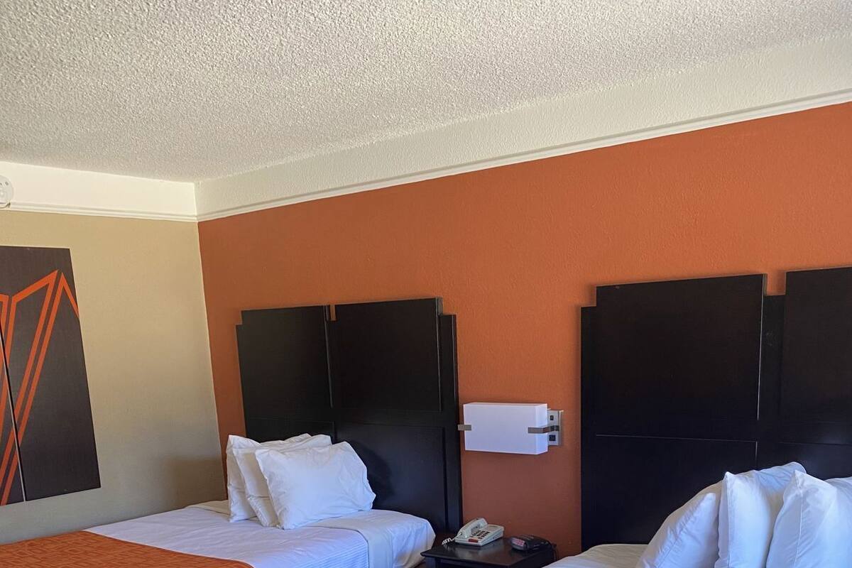 Ein Hotelzimmer mit zwei Betten, einem Telefon und einer wandmontierten Lampe.