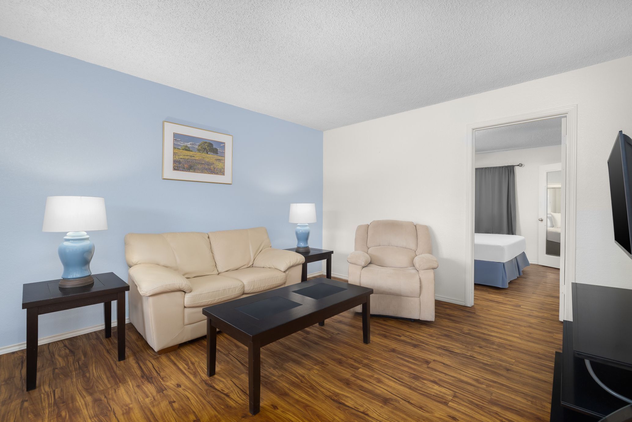 A living room with a sofa, armchair, coffee table, and lamps.