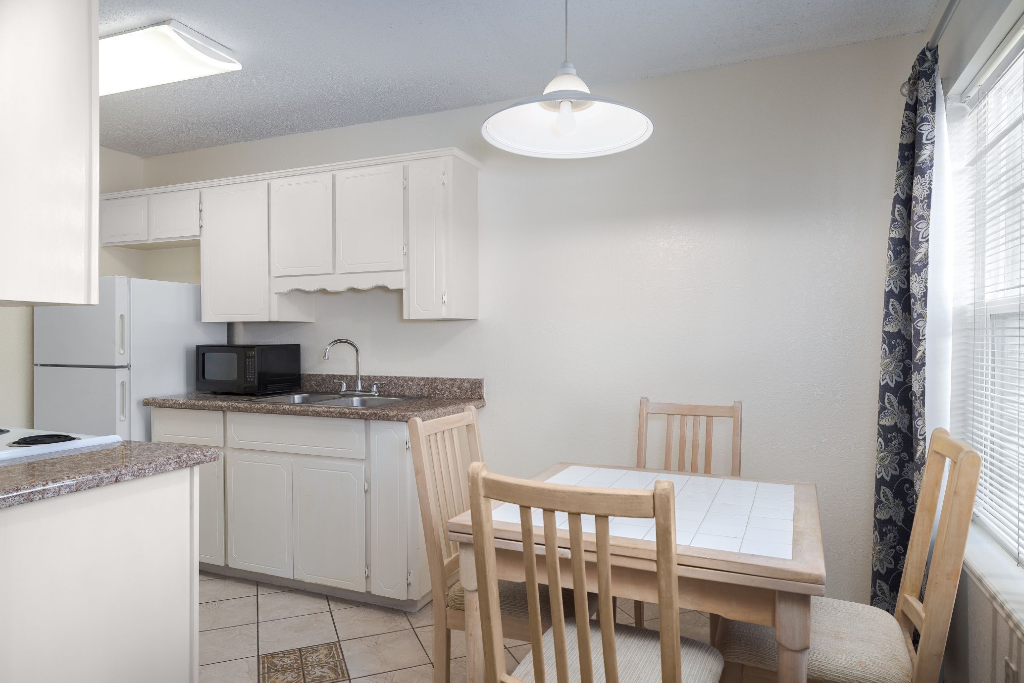 A kitchen with white cabinets, a microwave, a sink, and a dining table with chairs.