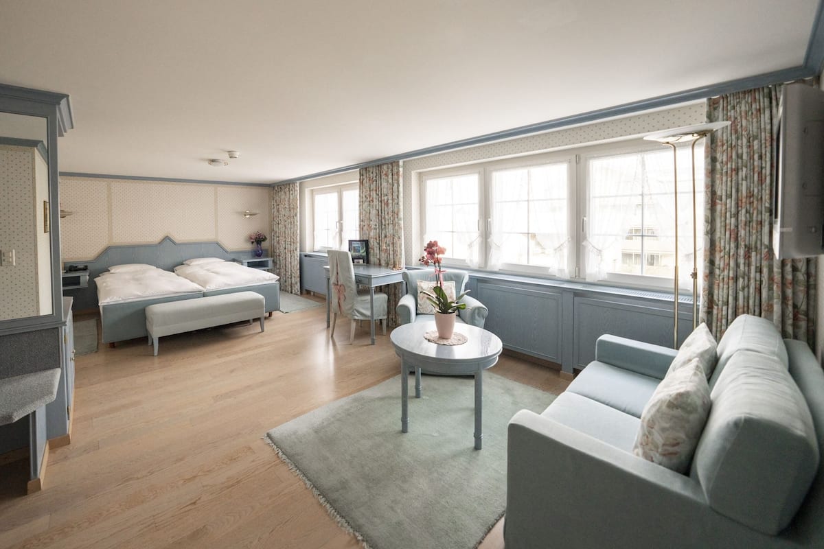 Una habitación de hotel moderna con una cama, un sofá, una mesita y un escritorio.
