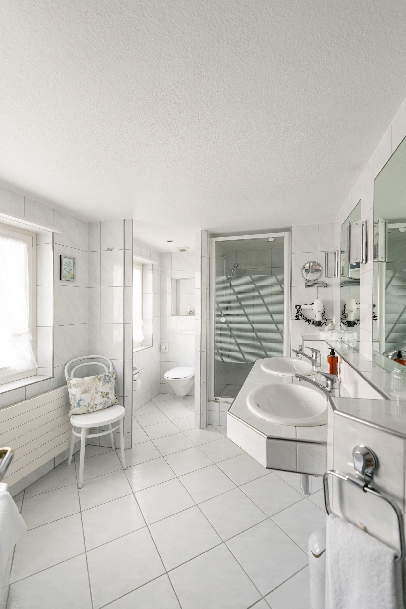 Un bagno moderno con lavandino, specchio e water bianchi.