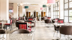 A spacious restaurant with multiple dining tables and chairs, large windows, and hanging pendant lights. - Sheffield Metropolitan Hotel by Belvilla (Sheffield)