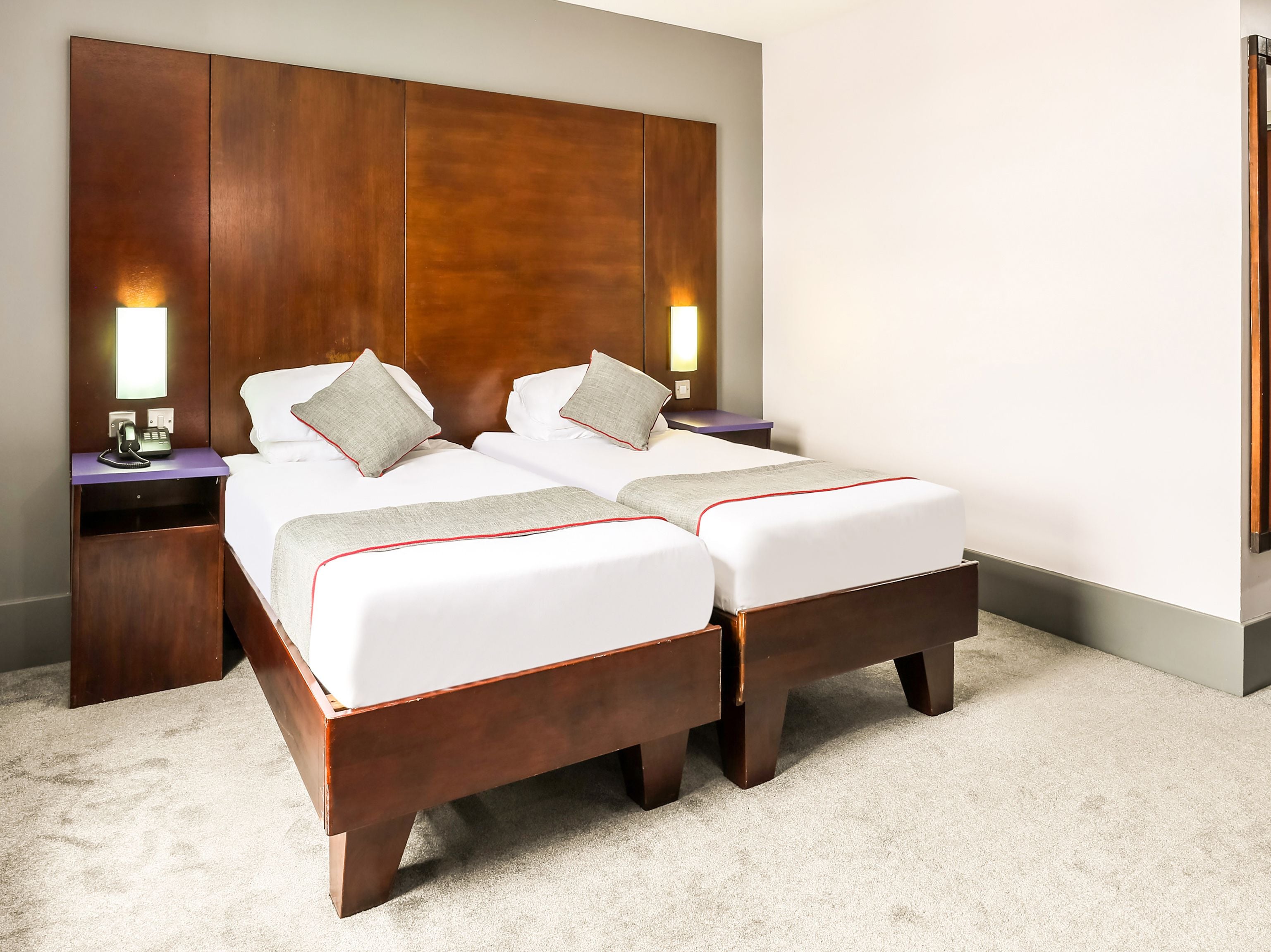 A double bed with a wooden headboard, two bedside tables with lamps, and a carpeted floor.