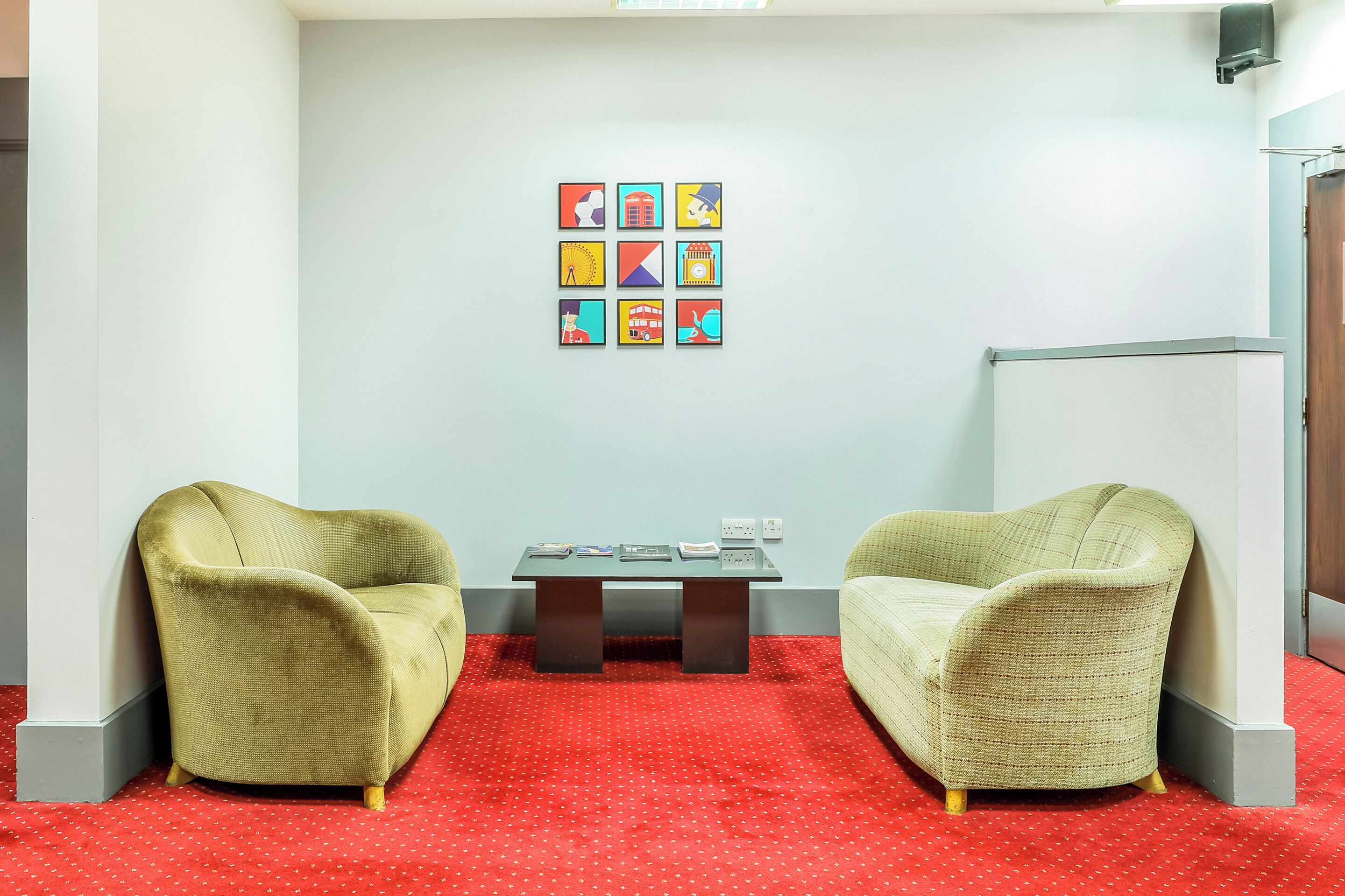 A room with two armchairs, a small table, and a wall with colorful artwork.