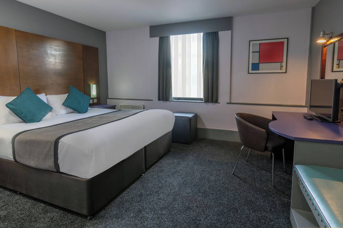 Una habitación de hotel con una cama grande, un escritorio y una silla.