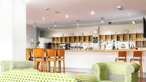 A modern interior with a bar area, wooden chairs, and a patterned sofa. - Sheffield Metropolitan Hotel by Belvilla (Sheffield)