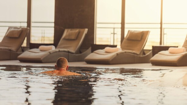 A pool area with lounge chairs and a person swimming. - Carnoustie Golf Hotel (Carnoustie)