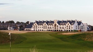 A golf course with a clubhouse featuring a clock tower and multiple windows. - Carnoustie Golf Hotel (Carnoustie)