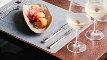 Una mesa de comedor dispuesta con un plato de comida, copas de vino, cubiertos y una servilleta.