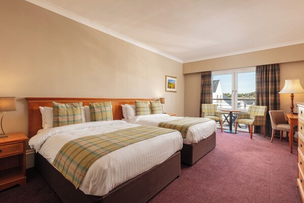A hotel room with two beds, a small table, chairs, and a view of the outside. - Carnoustie Golf Hotel (Carnoustie)