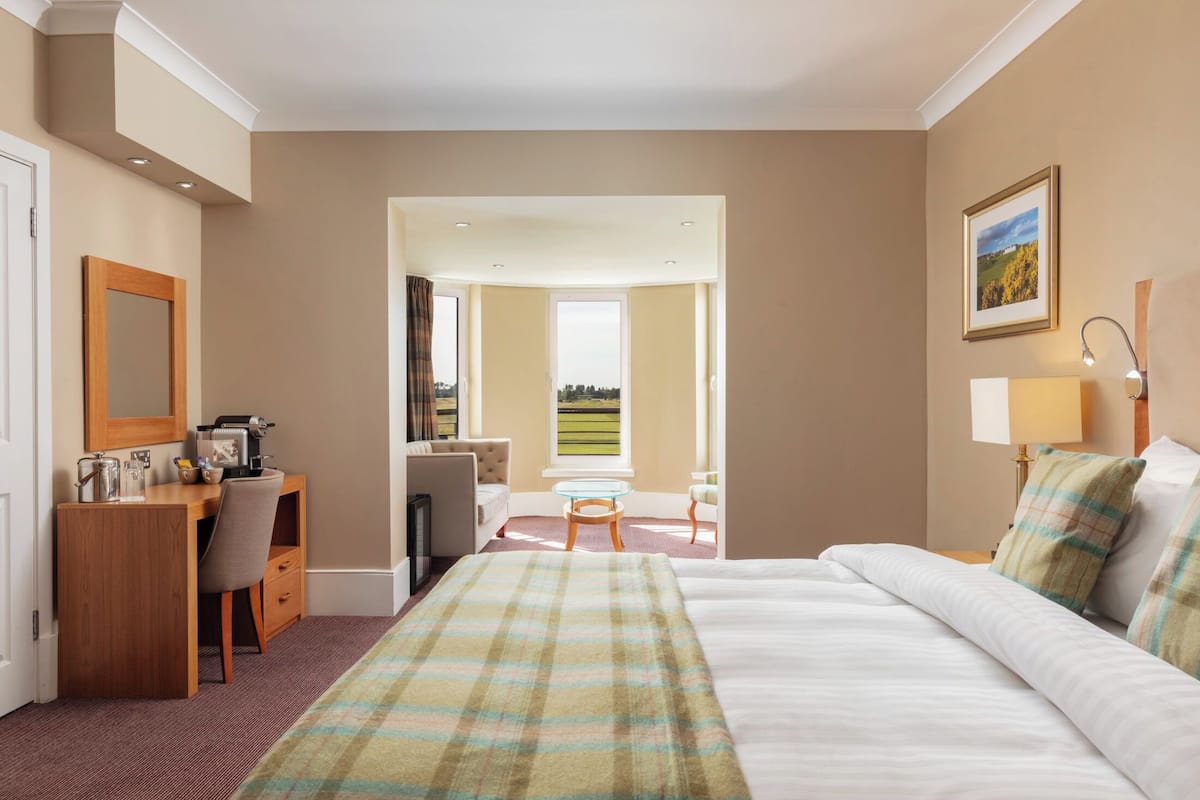 Habitación de hotel con una cama, un escritorio con una silla, una mesita y vistas al exterior.