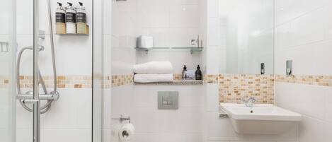 A modern bathroom with a glass-enclosed shower, a white toilet, a sink, and a mirror.