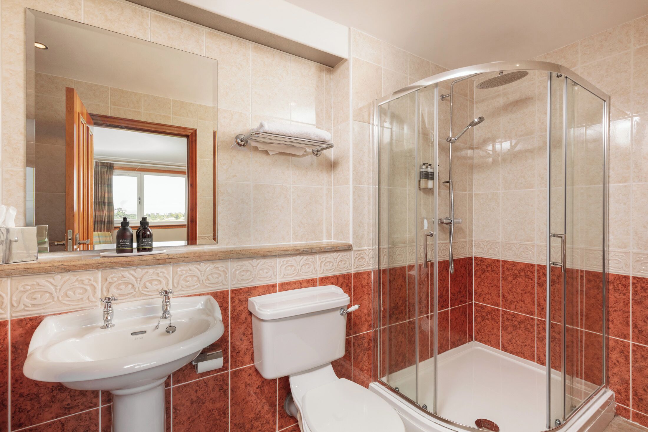 Un baño con ducha acristalada, lavamanos e inodoro.