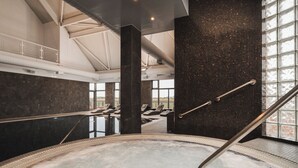 A modern indoor pool area with a large, heated pool, lounge chairs, and a high ceiling with skylights. - Carnoustie Golf Hotel (Carnoustie)