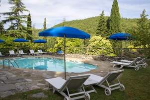Zona de piscina con sillas de descanso y sombrillas azules.