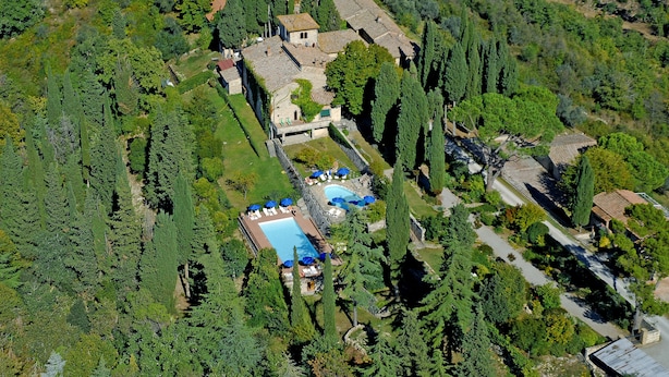 Vista aèria d'un complex turístic amb piscina, envoltat de vegetació abundant i arbres alts.