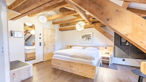 A bedroom with a wooden ceiling, a bed, a bedside table, and a wall-mounted clock. - Hotel Stern Chur (Chur)