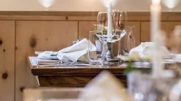 A dining table set with white napkins, wine glasses, and a candle.