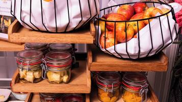 Un buffet de petit-déjeuner avec des saladiers de fruits, des pots de confitures et un présentoir contenant des couverts.