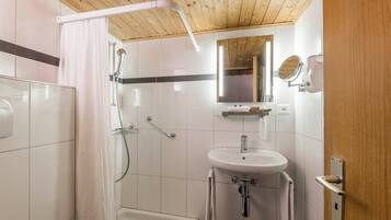 A bathroom with a shower, bathtub, sink, and a mirror.