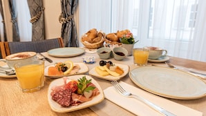A breakfast table with croissants, cheese, ham, and a fruit plate. - Hotel Stern Chur (Chur)