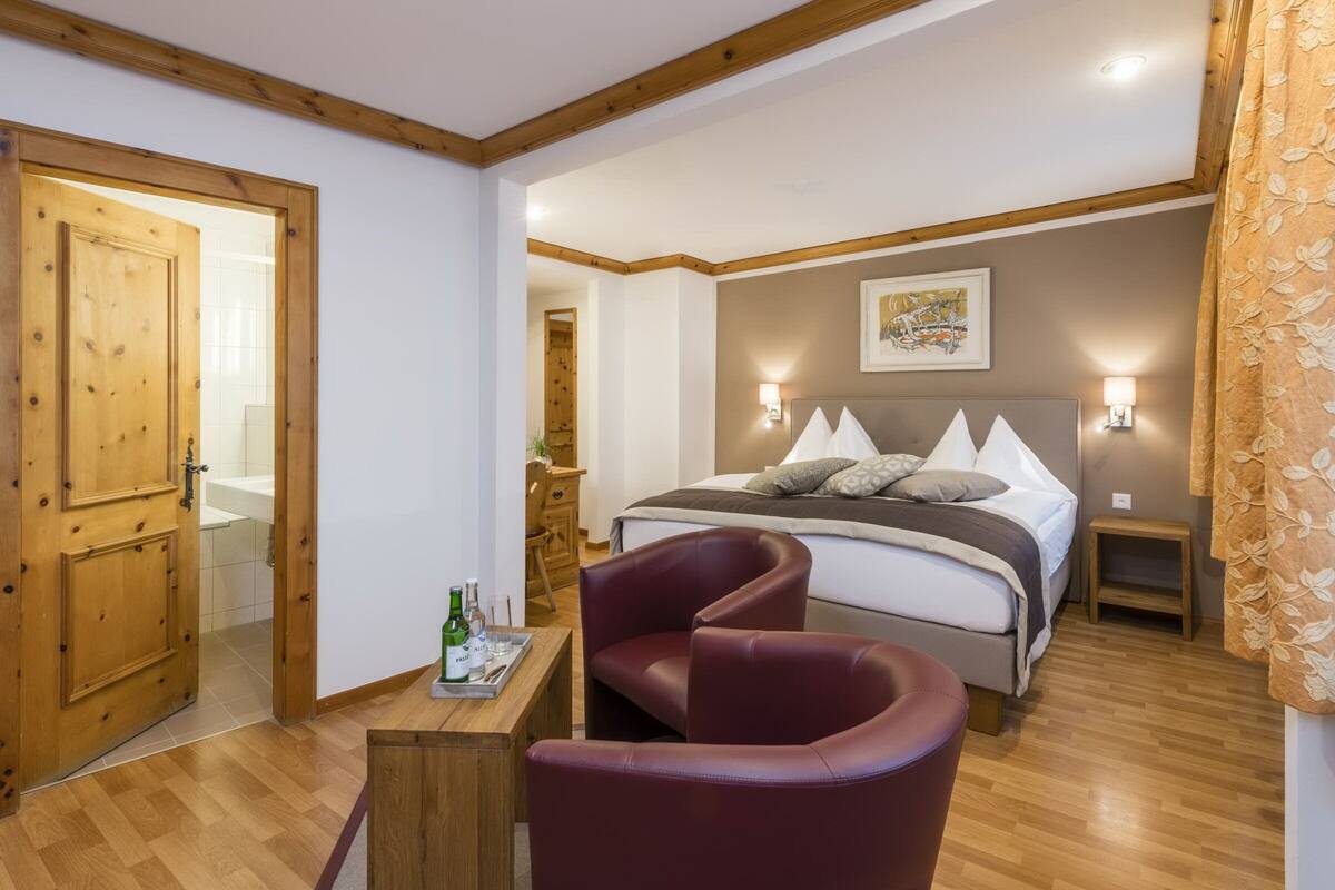 Un dormitorio con cama, mesitas de noche, una silla y una puerta de madera.