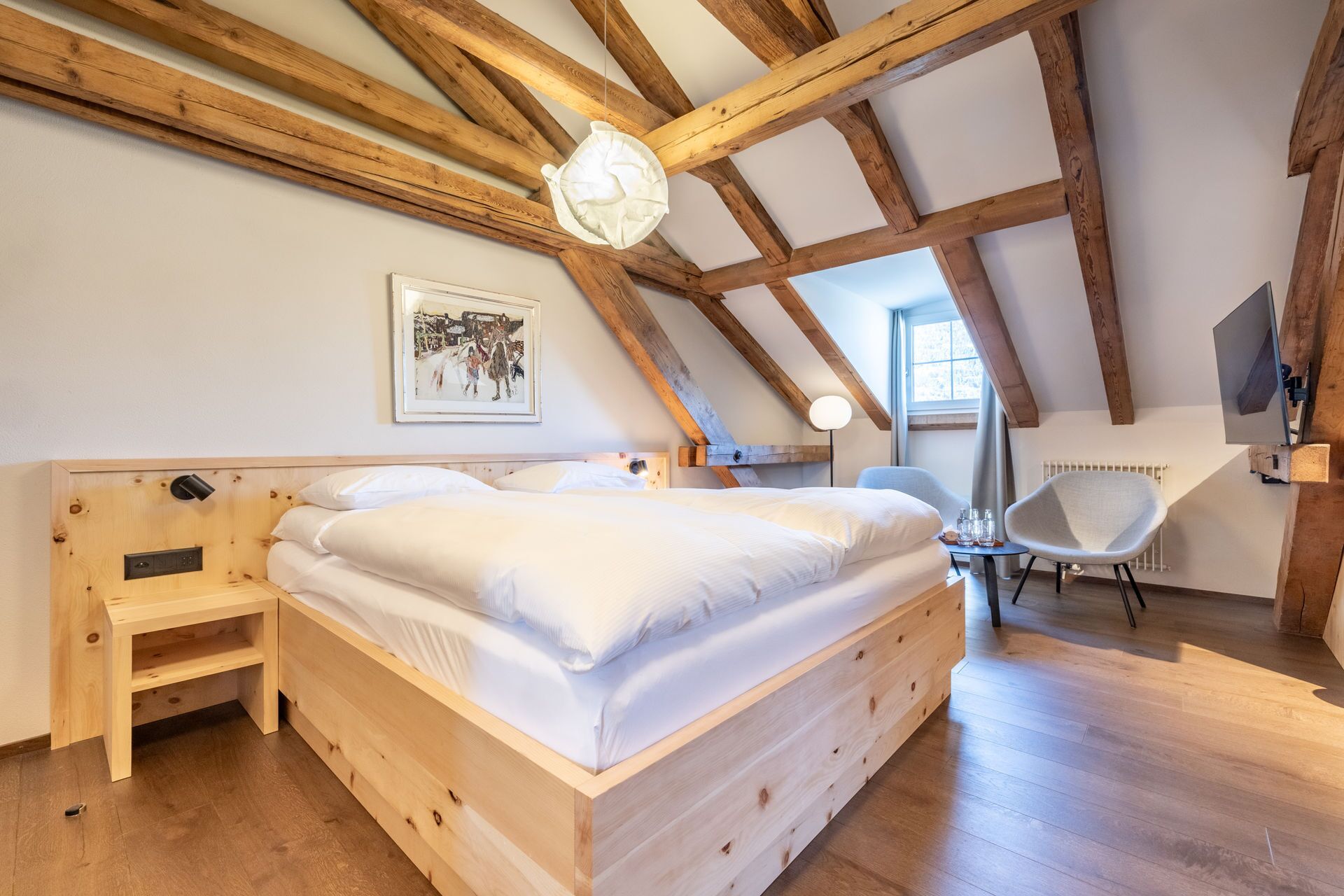 A bedroom with a wooden bed, a small bedside table, a chair, and a ceiling fan.