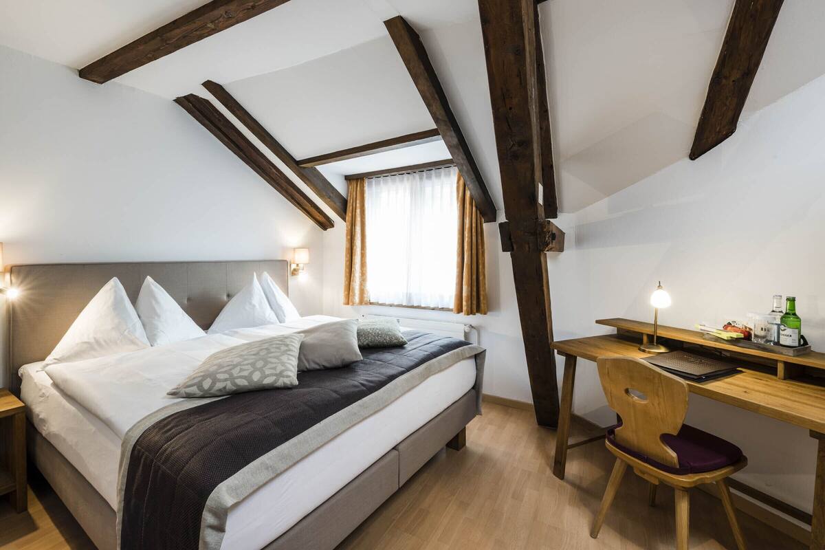 Un dormitorio con cama, mesitas de noche, un escritorio y una silla.