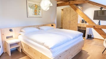 Una cama de madera con ropa de cama blanca en una habitación con techo y paredes de madera.