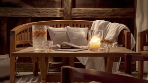 A wooden table with a candle, a pitcher, and glasses.