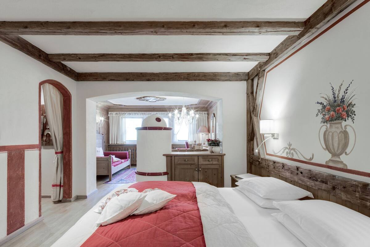 Een slaapkamer met een groot bed, houten balken, een kast en een spiegel.