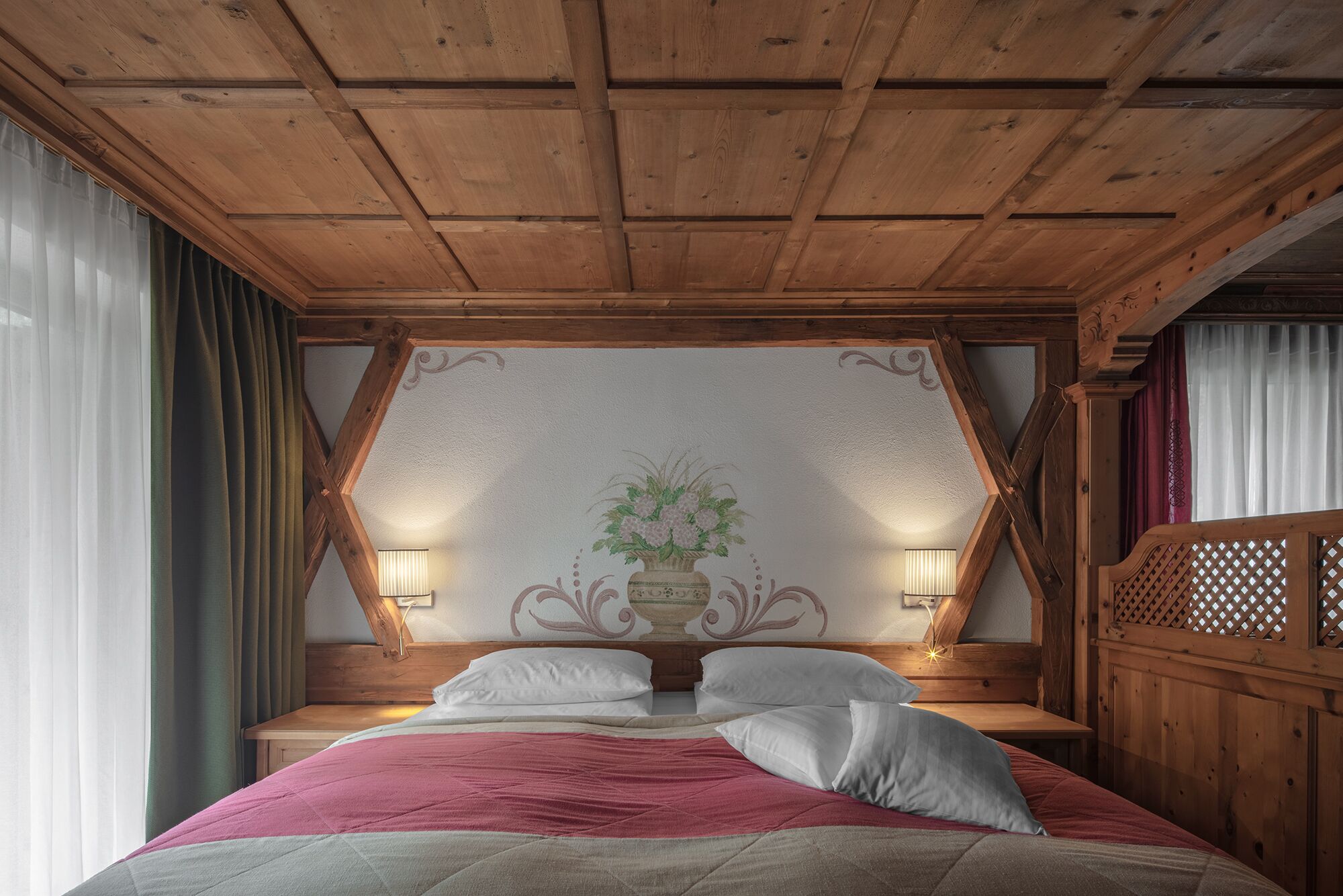 A wooden-framed bedroom with a bed, two bedside lamps, and a decorative wall panel.