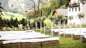 A rural wedding venue with hay bales, white tablecloths, and floral decorations.