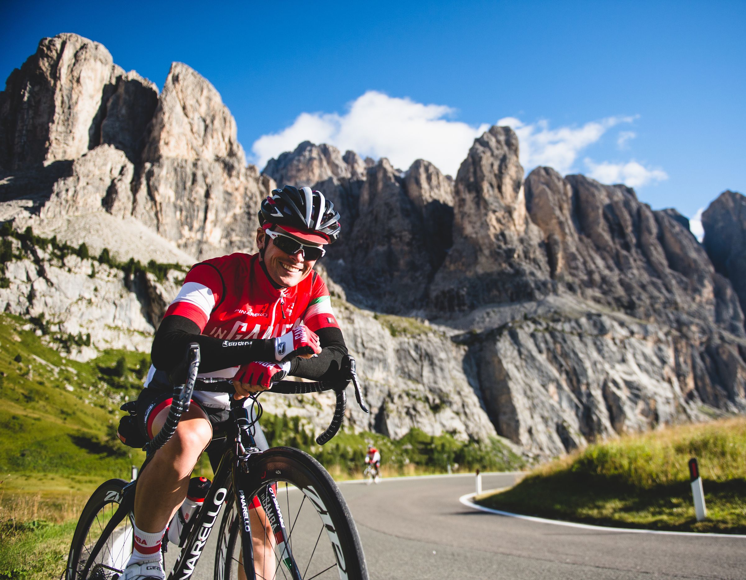 Un ciclista su una strada con montagne sullo sfondo.