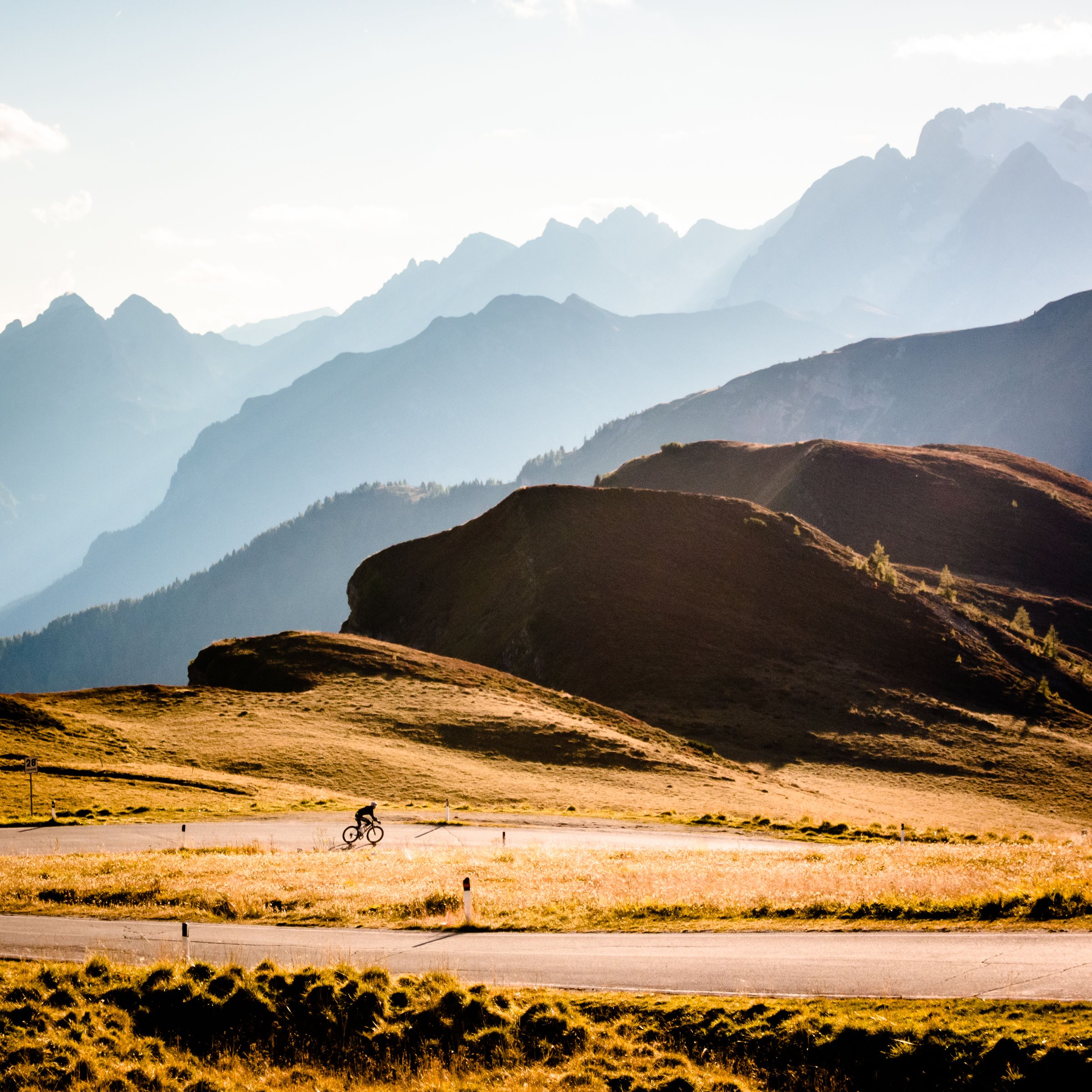 A cyclist on a road with a mountainous backdrop.