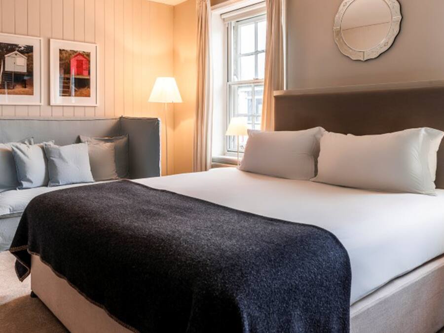 Une chambre d’hôtel avec un grand lit, une table de chevet, une lampe et deux tableaux encadrés au mur.