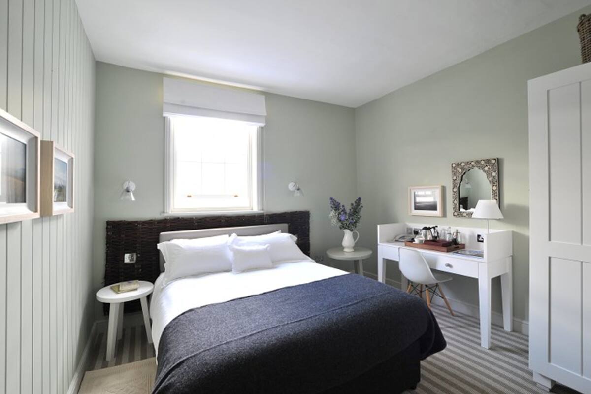 Une chambre d’hôtel avec un lit, un bureau, une chaise, une petite table et une fenêtre.