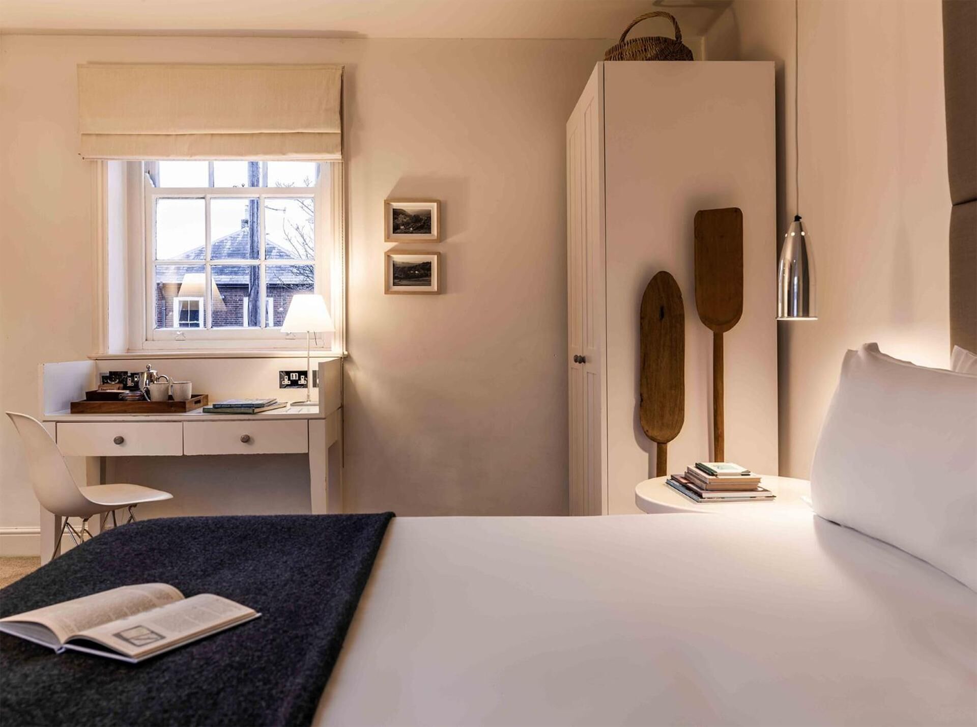 Un dormitorio con cama, escritorio, silla, ventana y armario.